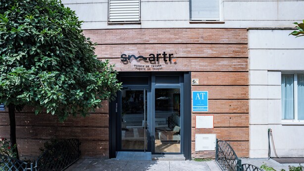 Ein Gebäude mit einem Schild, das ‚smart‘ anzeigt, einem gut sichtbaren Eingang und einem blauen AT-Zeichen.