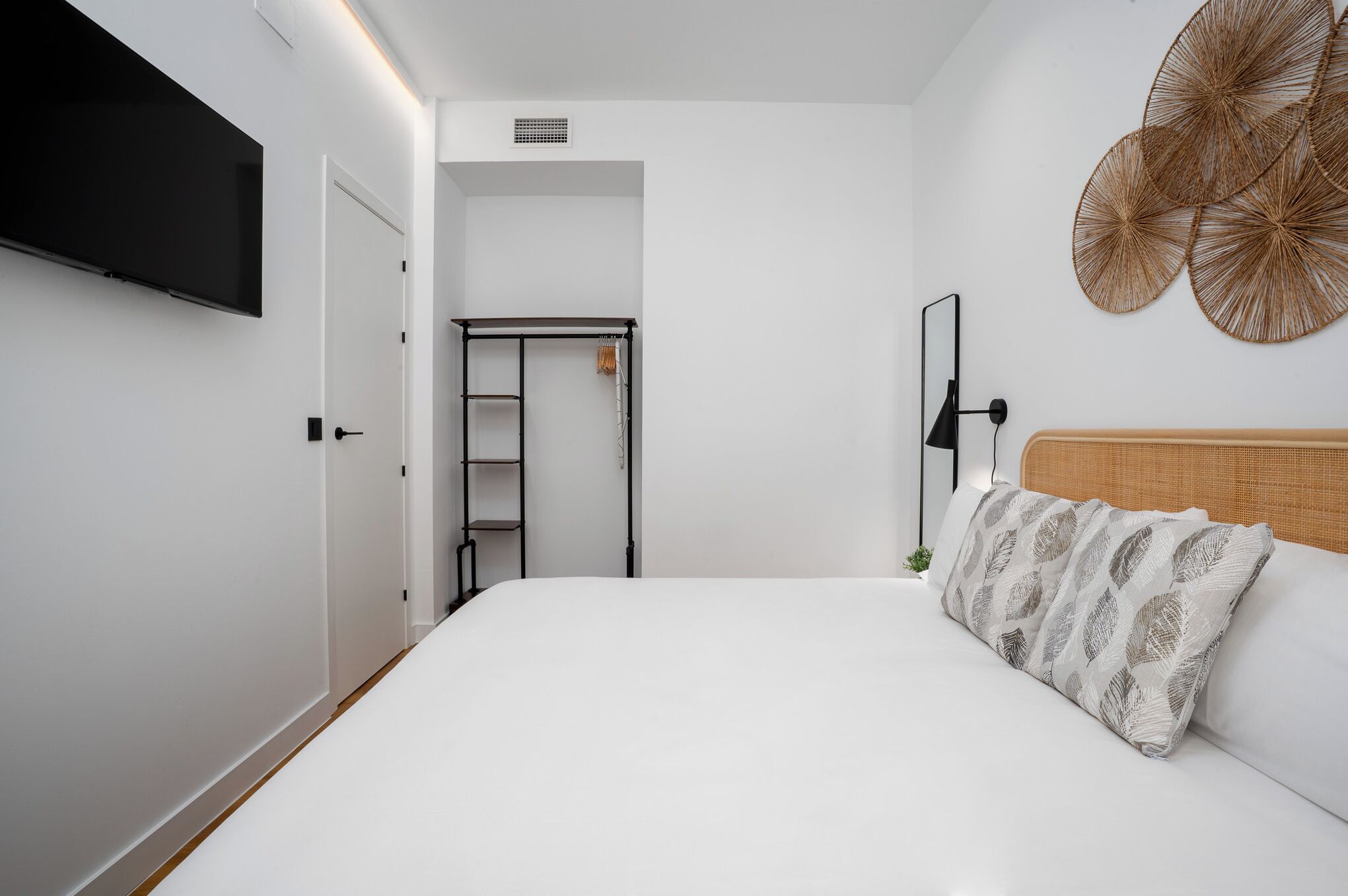 Une chambre à coucher comprenant un lit, un téléviseur fixé au mur, une armoire et un élément décoratif mural.