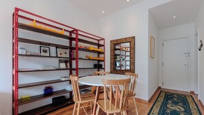 A dining area with a round table and wooden chairs, surrounded by red metal shelves with various items. - Vista Carioca (Rio de Janeiro)