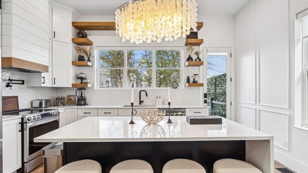 A modern kitchen with a large island, white cabinetry, and a decorative chandelier. - Luxury Spa Retreat | Sauna, Hot Tub & Fire Pit (Nashville)