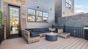 An outdoor deck with a sofa, two side tables, and a fire pit. - Luxury Spa Retreat | Sauna, Hot Tub & Fire Pit (Nashville)