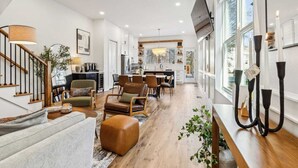 A spacious living room with a staircase, a dining area, and a kitchen. - Luxury Spa Retreat | Sauna, Hot Tub & Fire Pit (Nashville)