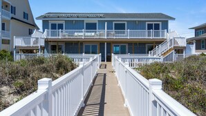 A beachfront property with a central entrance, multiple balconies, and a wooden deck. - 4 BR Oceanfront Carolina Clipper East has Updated Kitchen with OF Views (Emerald Isle)