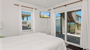 A bedroom with a bed, a television, and a view of the outdoors. - 4 BR Oceanfront Carolina Clipper East has Updated Kitchen with OF Views (Emerald Isle)