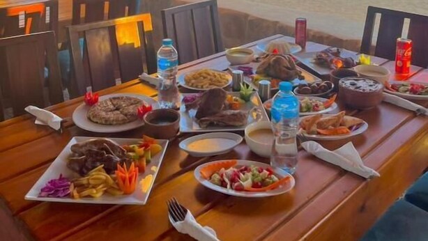 A table set for a meal with various dishes and drinks, overlooking a beach. - Tache By The Lake (El Faiyum)
