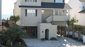 Une maison à deux étages avec un balcon, un garage et une allée pavée de sable.