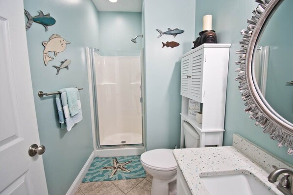 A bathroom with a shower, toilet, and sink. There are starfish and fish decals on the walls.