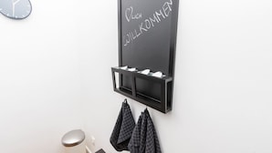Eine Tafel mit der Aufschrift 'Willkommen', eine Uhr und ein Handtuchhalter mit Handtüchern.