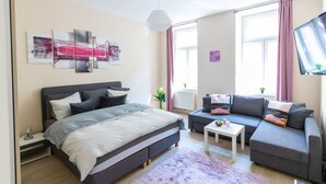 A modern bedroom with a bed, sofa, and a TV.