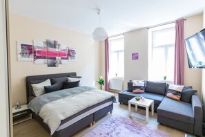 Quarto moderno com cama, sofá e televisão.