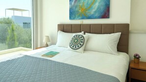 Ett hotellrum med en stor säng, utsikt över grönområden utanför och en tavla på väggen.