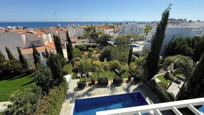 Ett bostadsområde med en swimmingpool, omgivet av grönska och byggnader.