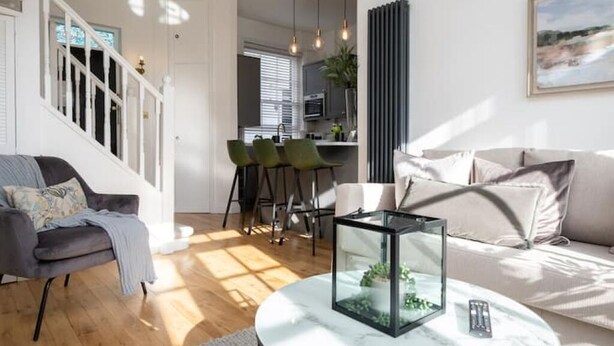 A modern living room with a sofa, a glass coffee table, and a staircase. - Beautiful Mews Cottage | 6 min walk to Rottingdean Beach | Near Brighton (Rottingdean)