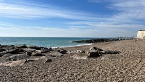 A rocky beach with waves crashing onto the shore, a clear sky, and a distant cliff. - Beautiful Mews Cottage | 6 min walk to Rottingdean Beach | Near Brighton (Rottingdean)