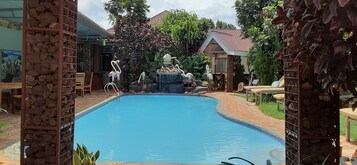Una piscina al aire libre, sombrillas, sillones reclinables de piscina