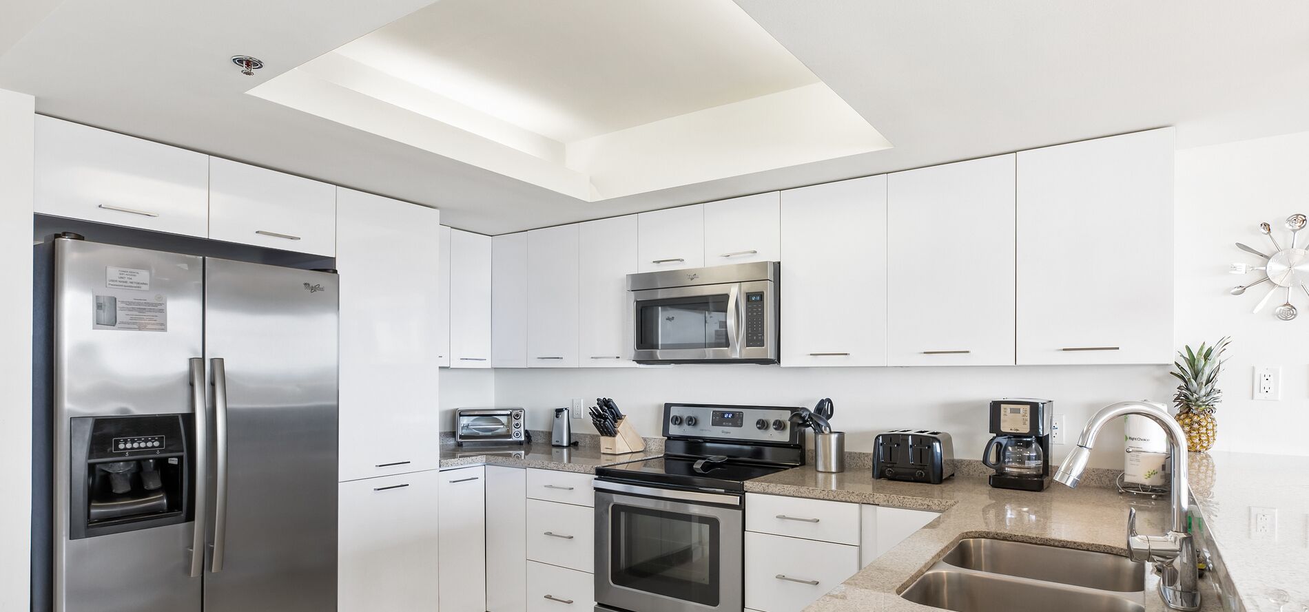 A modern kitchen with stainless steel appliances, white cabinetry, and a skylight.