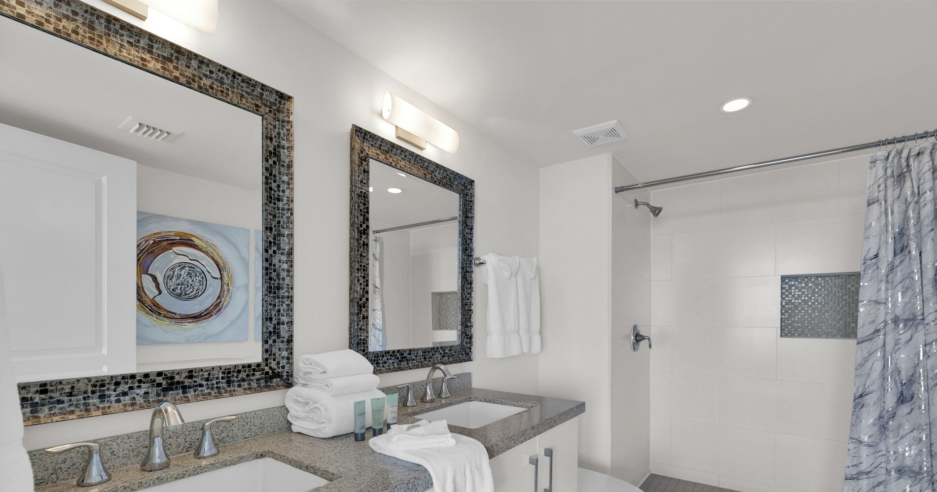 A modern bathroom with two sinks, a large mirror, and a shower.