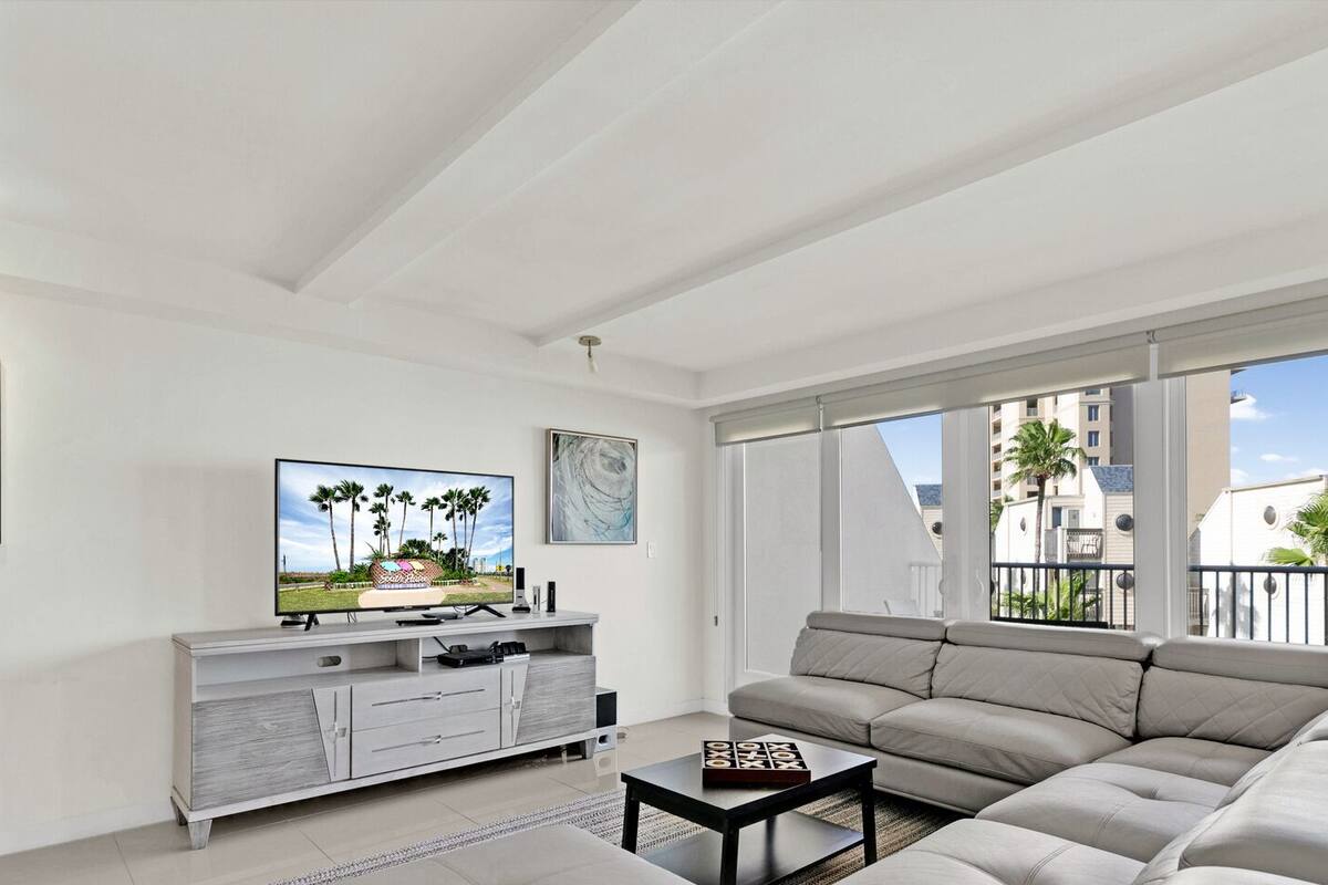 A spacious living room with a large sofa, a flat-screen TV, and artwork on the walls.