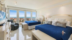 Une chambre d’hôtel avec deux lits, un bureau, une chaise et une vue sur l’océan.