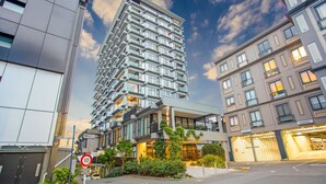 A modern high-rise building with multiple balconies and a ground-level commercial space. - Premium Cityscape Abode w Skytower view & Parking (Auckland CBD)