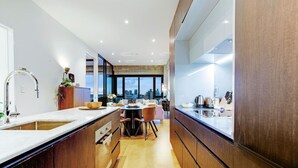 A modern kitchen with a large island, wooden cabinets, and a view of the cityscape. - Premium Cityscape Abode w Skytower view & Parking (Auckland CBD)