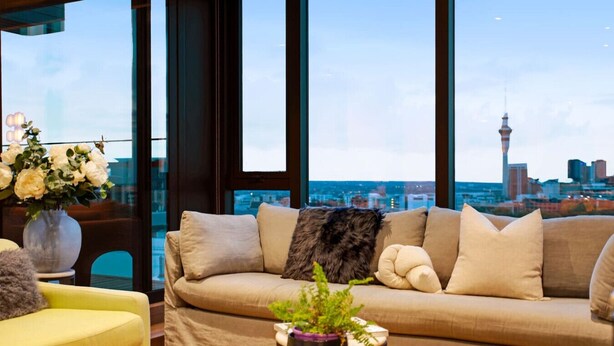 A modern living room with a sofa, yellow armchair, and a coffee table with a plant. - Premium Cityscape Abode w Skytower view & Parking (Auckland CBD)
