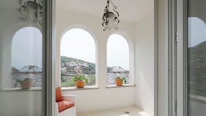A balcony with white wicker furniture and potted plants, overlooking a cityscape. - Le Cavottole Resort (Vico Equense)
