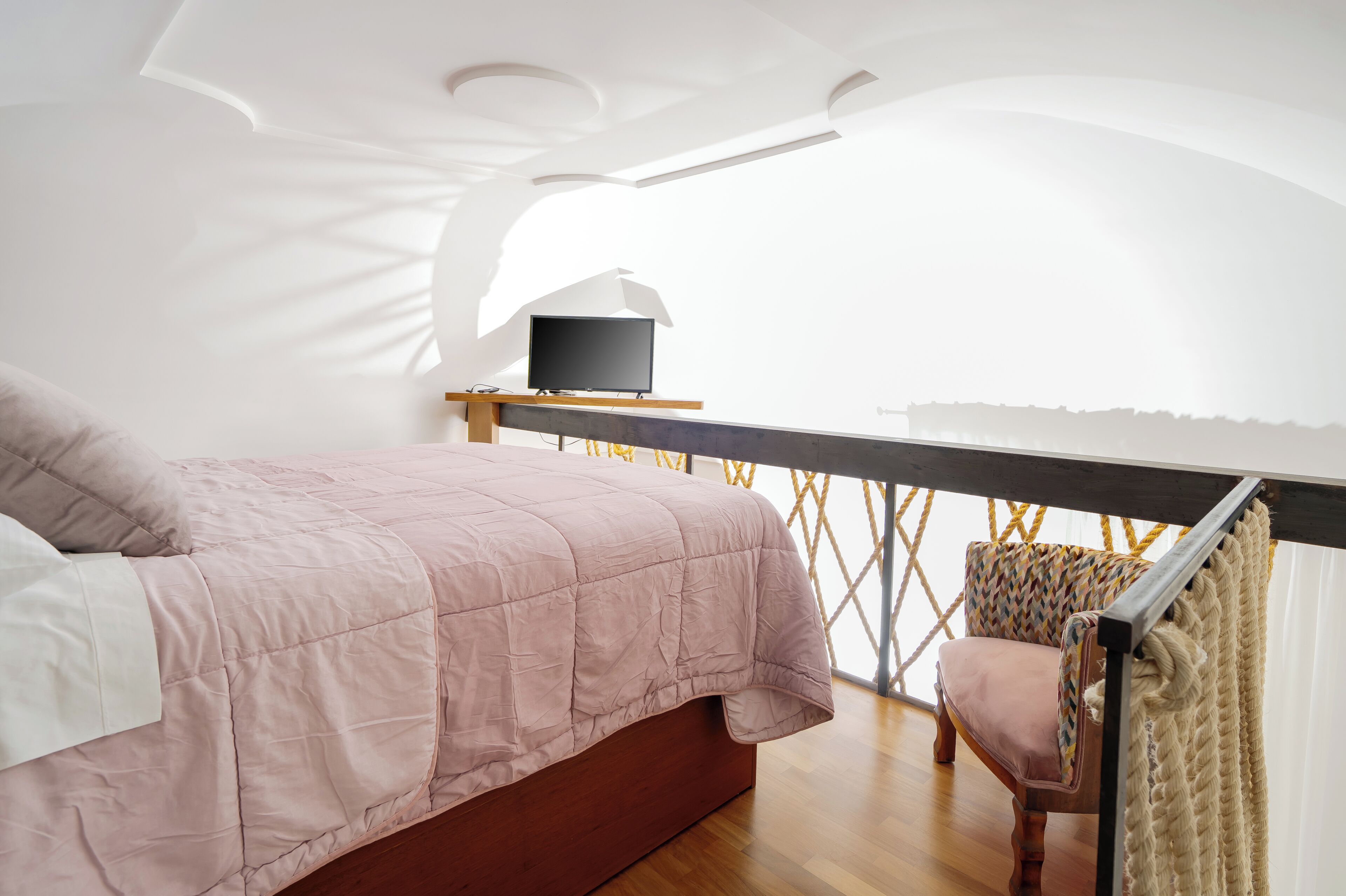Una camera da letto con un letto, una scrivania con televisore, una sedia e vista sull'esterno.