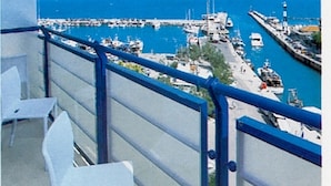 A balcony with a view of a marina with boats and a lighthouse.