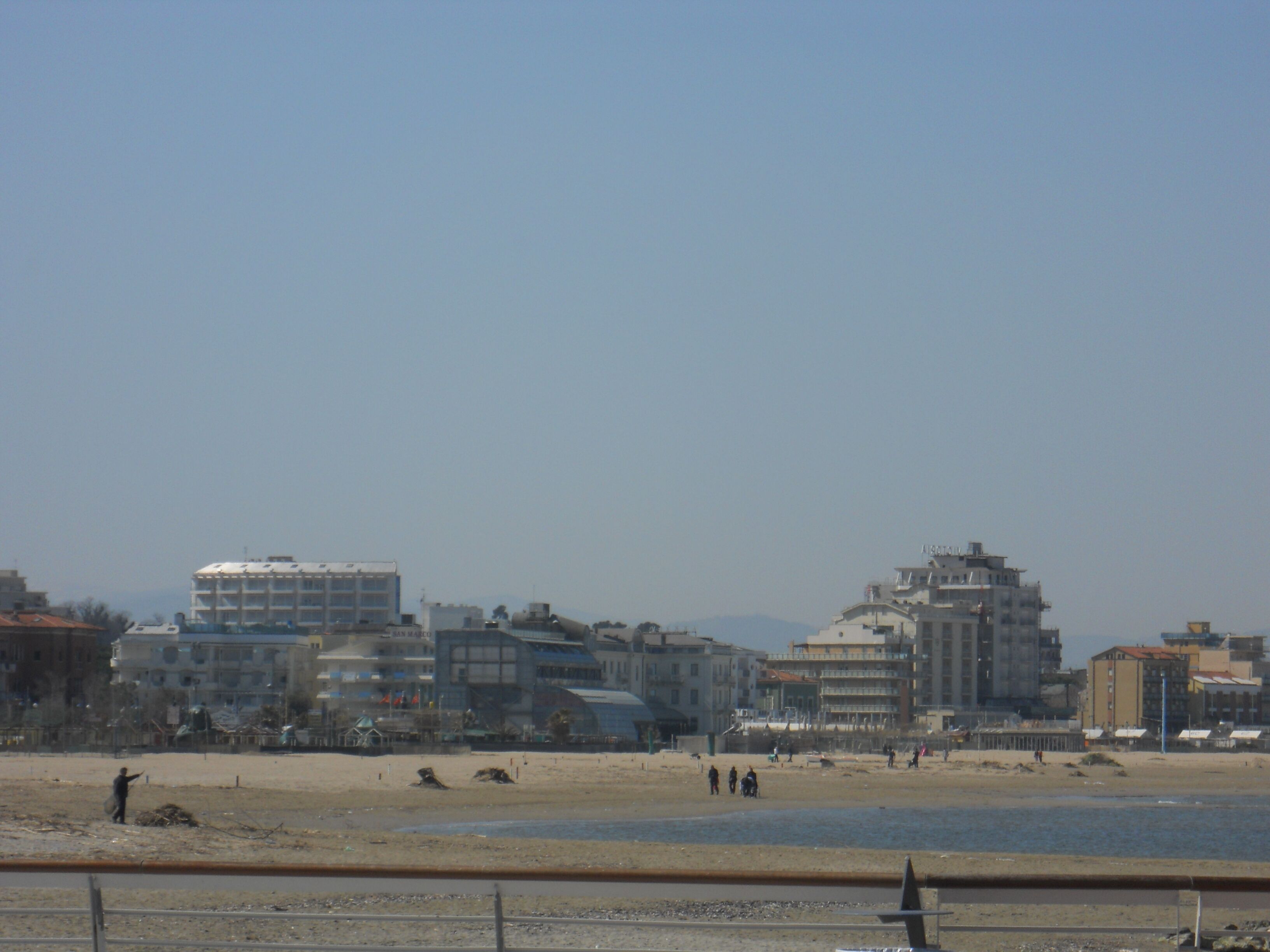 Eine Küstenstadtlandschaft mit Gebäuden, einem Strand und blauem Himmel.