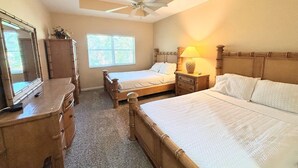 Un dormitorio con dos camas, ventilador de techo, cómoda y ventana con persianas.
