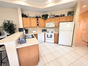 A modern kitchen with wooden cabinets, a white refrigerator, a microwave, and a stove.