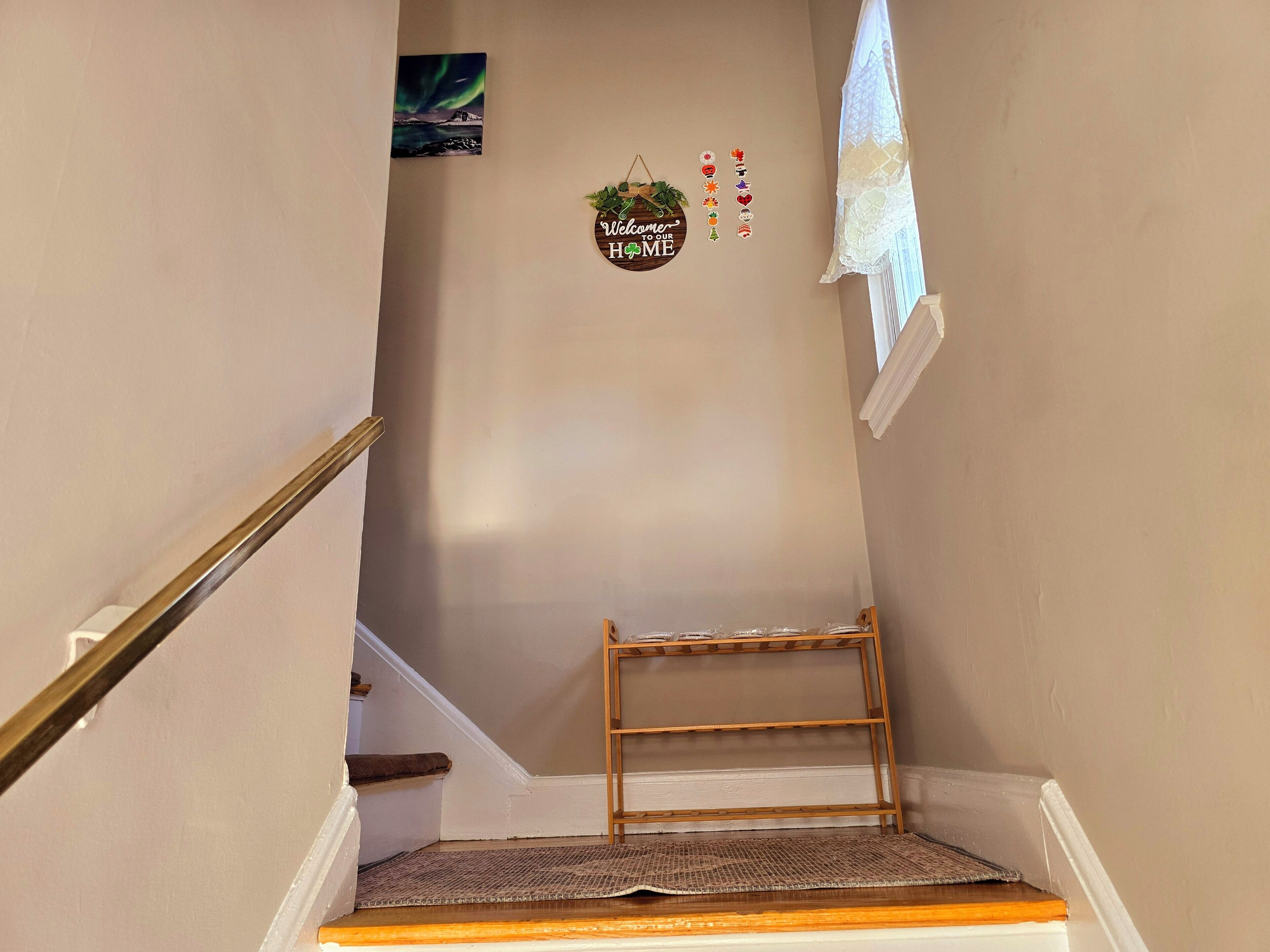 A staircase with a wooden handrail, a welcome sign, and a decorative wall hanging.