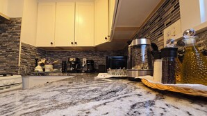A kitchen with granite countertops, a gas stove, and a coffee maker. - Under the Sun Apartment (Boston)
