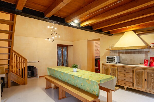 A cozy kitchen with wooden cabinets, a dining table with a bench, and a staircase. - Borgo Olivo by Wonderful Italy (Puegnago del Garda)