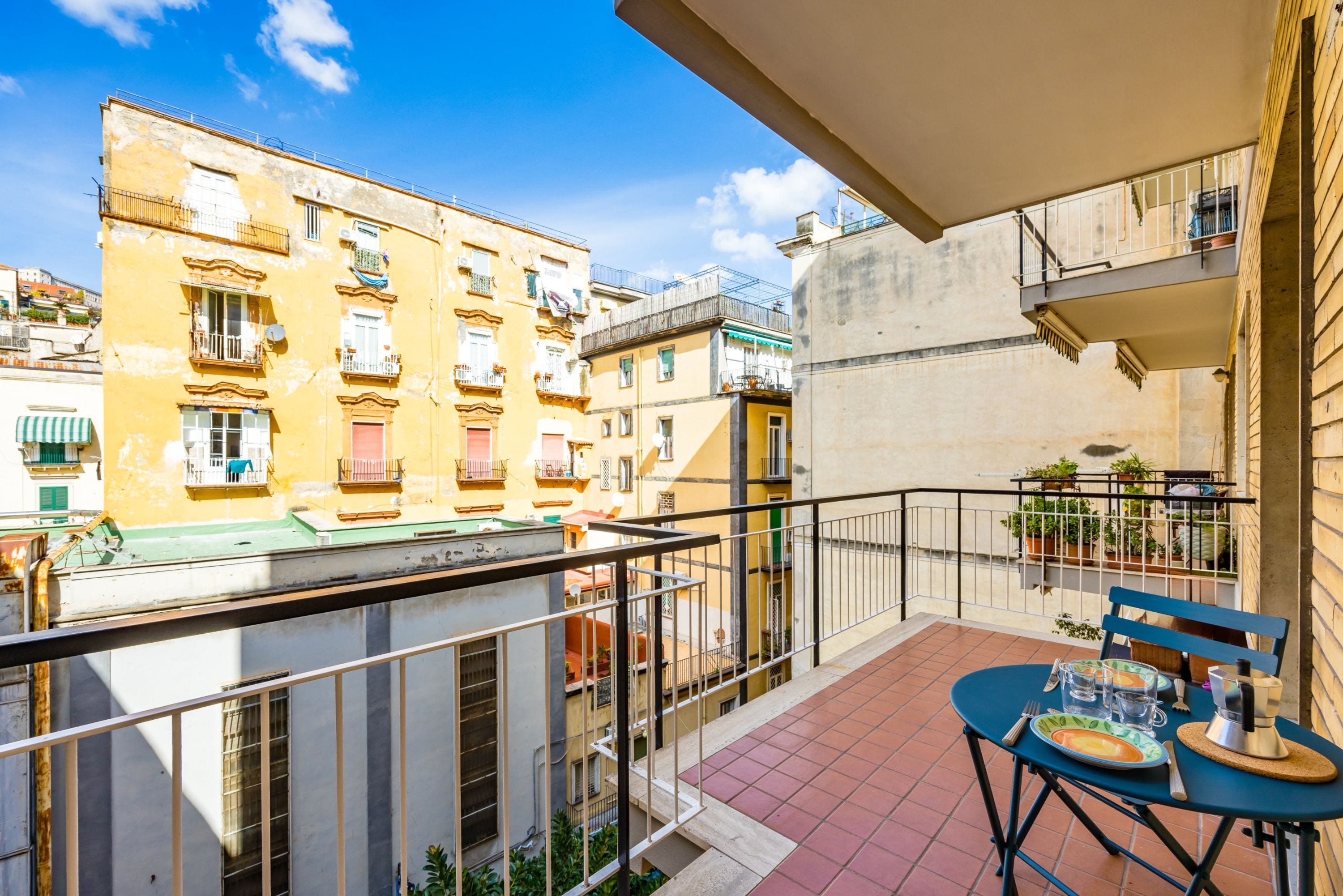 Ein Balkon mit Esstisch, mit Blick auf eine Stadtlandschaft und Gebäude.