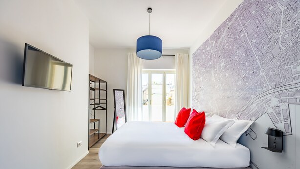 A modern hotel room with a large bed, a flat-screen TV, a blue pendant light, and a city map wall. - Street Stritt 60 by Wonderful Italy - Apt 2 (Naples)