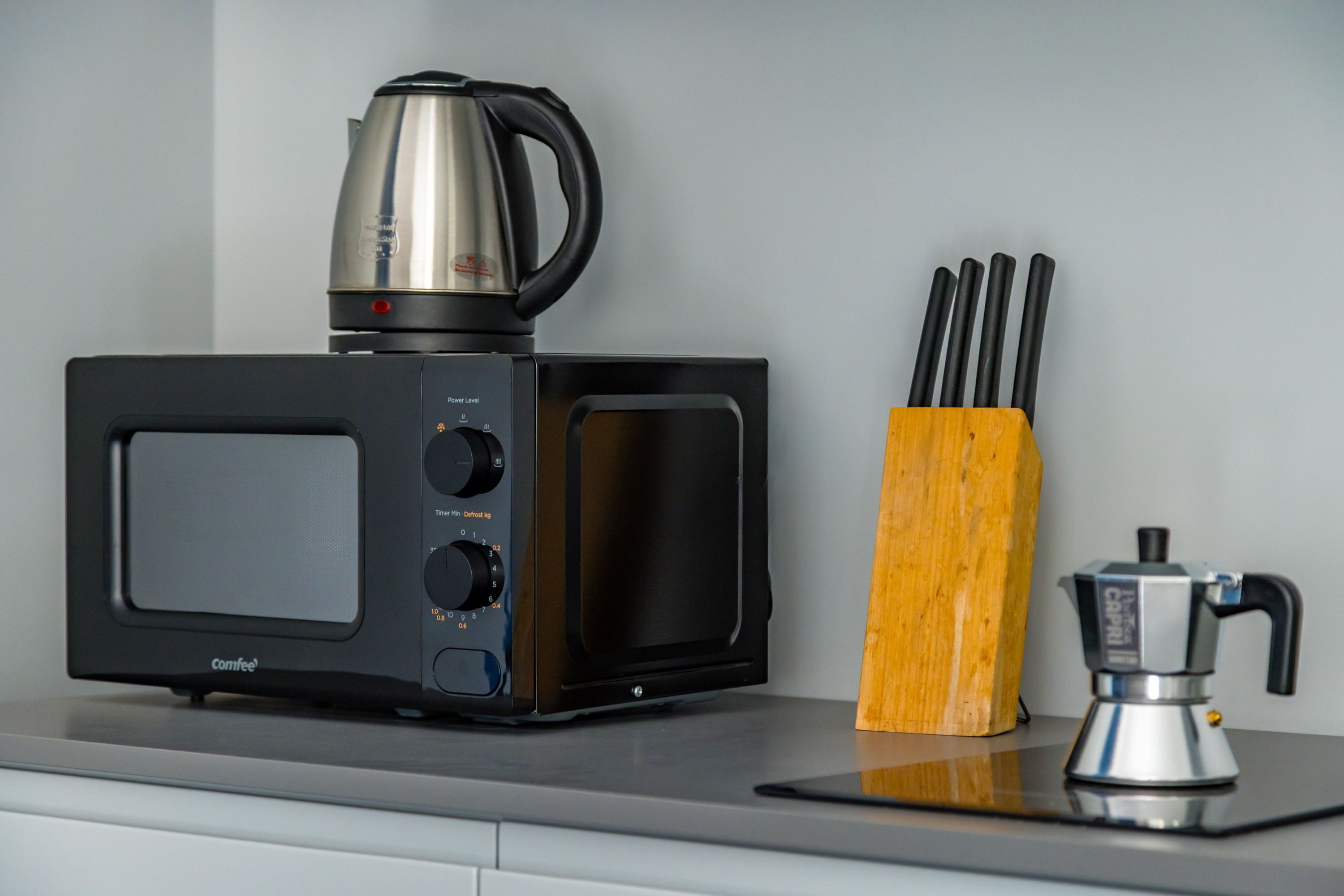 A kitchen with a Comfee microwave, a coffee maker, and a knife block.