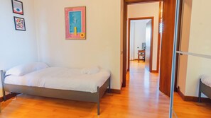 A bedroom with a bed, a wooden floor, and a door leading to another room. - Dimora dei Colori - Two Bedroom Apartment, Sleeps 6 (Sirmione)