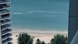 Une vue d’une plage avec une piscine et un immeuble de grande hauteur au premier plan.