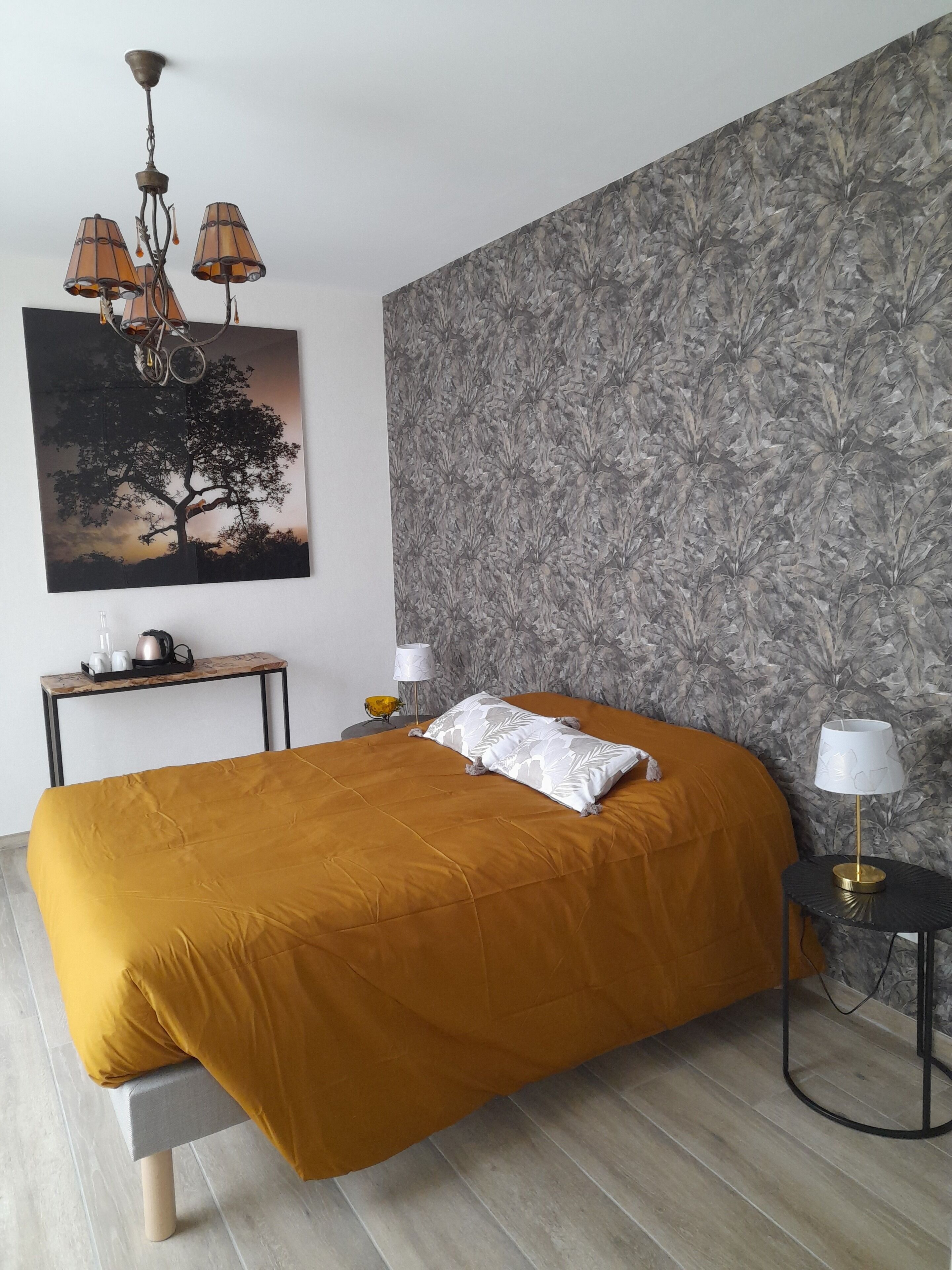 Een slaapkamer met een groot bed, een nachtkastje, een lamp en een wanddecoratie.