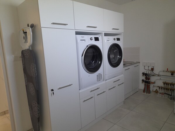 A laundry room with two front-loading washing machines, a drying machine, and a water heater.