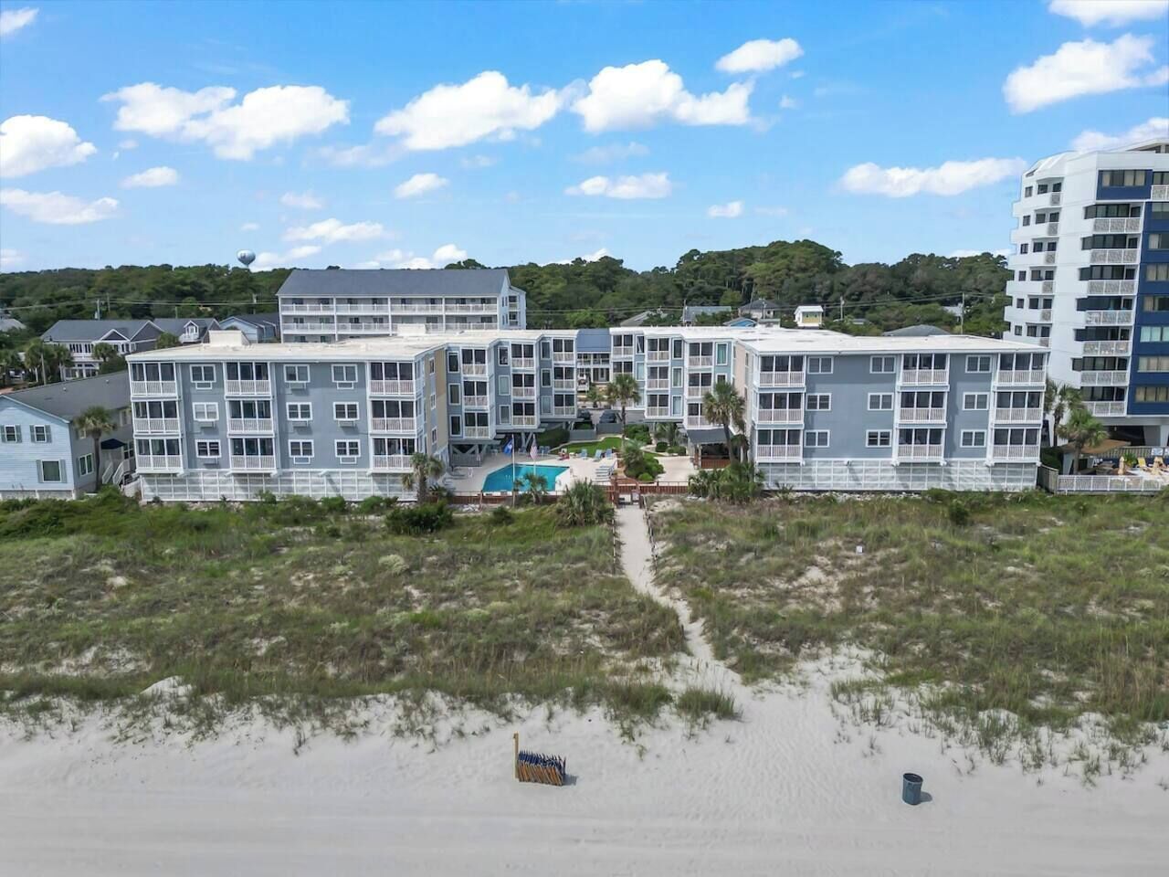 Een hotel aan het strand met meerlaagsgebouwen, een zwembad en een zandstrand.