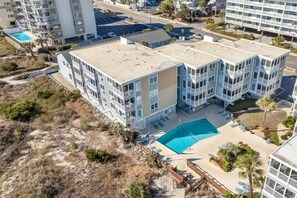 Un hotel de varios pisos con piscina en la azotea y zona de playa.