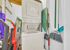 A laundry room with a washing machine, a dryer, and various cleaning tools.