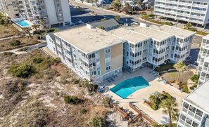 A multi-story hotel with a rooftop pool and a beach area.