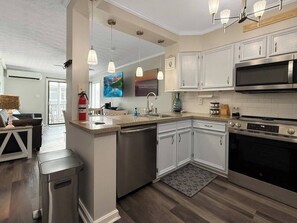A modern kitchen with white cabinetry, stainless steel appliances, and pendant lighting.