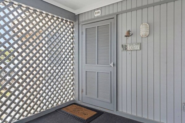 A grey door with a sign reading 'Welcome to our beach house' and a number '306' above it.