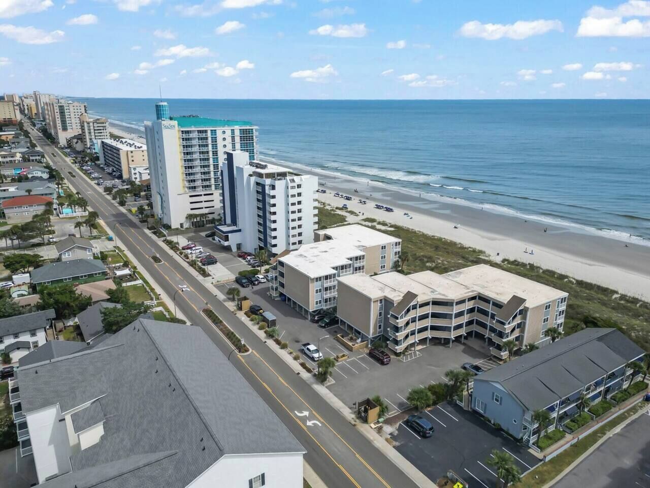 Un hôtel situé sur la côte, composé de plusieurs bâtiments, doté d’un parking et offrant une vue sur la plage.