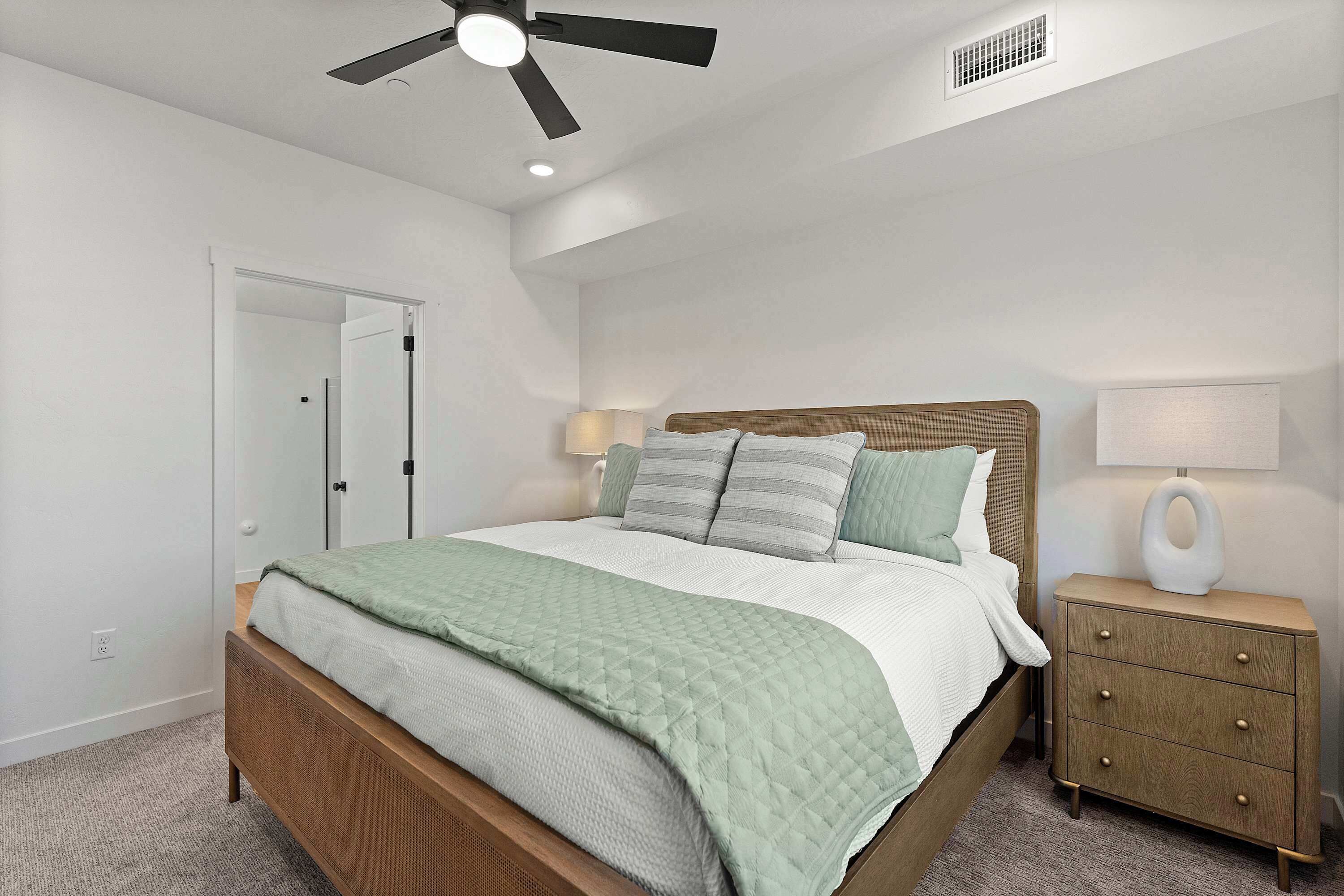 A bedroom with a bed, bedside lamps, a nightstand, and a ceiling fan.